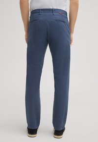 Pantaloni blu navy realizzati in un tessuto leggero, dotati di due tasche posteriori, con un taglio dritto e una superficie testurizzata.