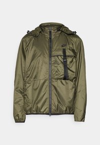 Olivgrön, lätt, vattenavvisande jacka med hög krage, frontdragkedja, bröstficka och justerbar dragsko i huvan. Svarta accenter.