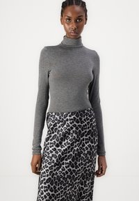 Pilka ilgam rankovėms turtleneck tipo palaidinė derinama su satino leopardų rašto sijonu, kuriame vyrauja juodi ir pilki motyvai, lygus paviršius ir prigludusi forma.
