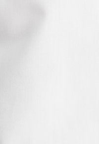 Effen wit stof met een subtiele geweven textuur en lichte schaduwwerking aan de linkerkant.