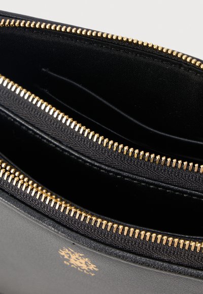 Čierna kožená peňaženka so zlatým zipsom, otvorená na zobrazenie vnútorných látkových priehradok a malého zlatého loga na vonkajšej strane.