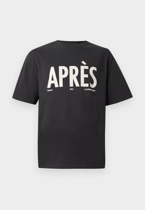 Melnas kokvilnas T-krekls ar lieliem baltiem burtiem "APRÈS", zem kuriem ir mazākā tekstā "GOLF" un "SKI". Klasiska apaļa kakla izgriezums un brīvs piegriezums.