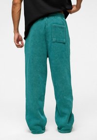 Tijgerkleurige corduroy broek met een relaxte pasvorm, voorzien van een elastische tailleband en een achterzak, zachte textuur en zichtbare stikseldetails.