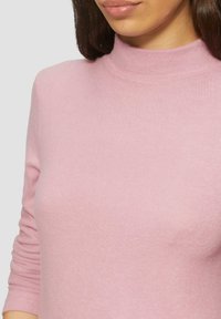 Jasnoróżowy sweter z golfem wykonany z miękkiej dzianiny. Posiada długie rękawy i dopasowany krój z ribbowanym wzorem przy dekolcie.