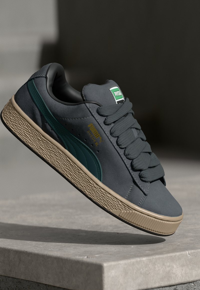 Sapatilha de camurça cinza com detalhes verdes e marcação em dourado. Sola de borracha tátil cor de tan espessa; atacadores redondos; design de baixo corte.