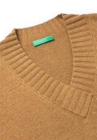 Brauner V-Ausschnitt-Pullover mit geripptem Kragen und Struktur. Das Etikett trägt "United Colors of Benetton." Weiches Strickmaterial, lässiges Design.