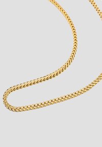 Guld hængekæde med snoede led, glat overflade og ensartet tykkelse, der elegant hænger mod en lys baggrund.