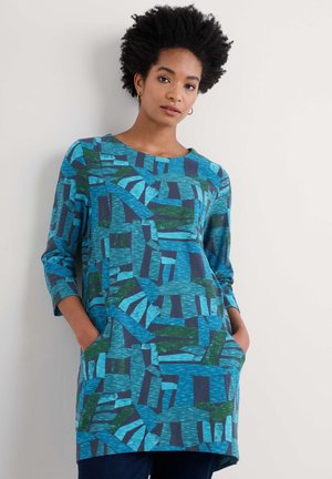 Blaue Tunika mit abstrakten geometrischen Mustern in Grün und Dunkelblau. Verfügt über Dreiviertelärmel und Seitentaschen. Weicher Stoff.