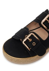 Čierne platformové sandále s semišovou textúrou, dvoma širokými remienkami so zlatými prackami a pletenou jútovou podrážkou s hladkým povrchom.
