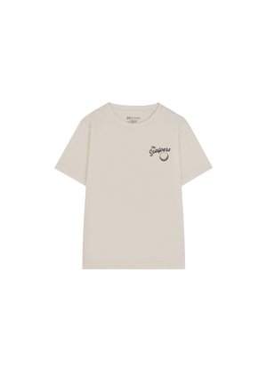Camiseta de algodón beige de manga corta con cuello redondo y un pequeño logo impreso en negro en el lado izquierdo del pecho. Textura suave y corte relajado.