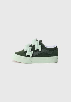 Baskets en suédine verte et toile avec des accents vert menthe et des sangles en forme d'éclair. Elles possèdent une semelle texturée et un doublure blanche.