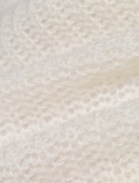 Witte gebreide stof met een zachte, pluizige textuur. Kenmerkt zich door een losse weefpatroon, wat zorgt voor een lichte en luchtige uitstraling.