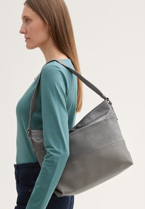 Sac à épaule en cuir gris avec une section supérieure texturée. Présente une section inférieure lisse et une sangle ajustable. Porté sur l'épaule.