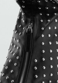 Borsa in pelle nera con borchie argentee e cerniera in metallo. Texture liscia con un motivo decorativo di borchie uniformemente distanziate.