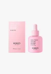 Botella de vidrio rosa con gotero, etiquetada como "SERUM SOOTHING BOOSTER DE SKIN TECH," junto a una caja rosa a juego, ambas con un diseño minimalista.