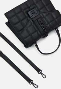 Musta tikattu nahkainen käsilaukku, jossa on ketjuyksityiskohta, yläkahva ja kaksi irrotettavaa olkahihnaa valkoista taustaa vasten.