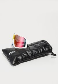 Sport-Sonnenbrillen mit weißen Rahmen und verlaufenden rosa Gläsern, auf einem schwarzen, gesteppten Beutel platziert. Enthält das Markenlogo "bliz."