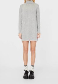 Graues langärmeliges Turtleneck-Kleid mit geradem Schnitt, kombiniert mit schwarzen Plateauschuhen und weißen Socken mit schwarzen Streifen.