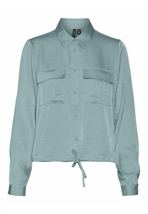 Blouse longue à manches longues en teal clair, en matière soyeuse, avec un devant à boutons, deux poches sur la poitrine et un détail à nouer au bord.