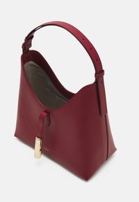 Sac à main en cuir bordeaux avec une texture lisse, une forme courbée, une courte bandoulière et des accents en métal doré. L'intérieur est en tissu gris.