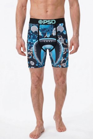 Male wearing blue and black boxer briefs with shark face and diamond chain patterns, standing barefoot against a white background.