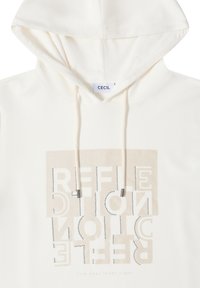 Sudadera blanca con un gráfico en el frente, que presenta la palabra "REFLEXIÓN" en color beige, adornada con tachuelas plateadas. Cuerdas ajustables con puntas metálicas.