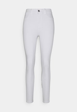 Jean skinny blanc taille haute avec une texture lisse, design à cinq poches, fermeture à boutons à l'avant et coupe ajustée sans coutures aux jambes.