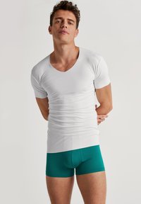 Witte katoenen V-hals t-shirt met korte mouwen gecombineerd met teal katoenen boxers, gladde textuur, aansluitend ontwerp en minimale merkbranding.