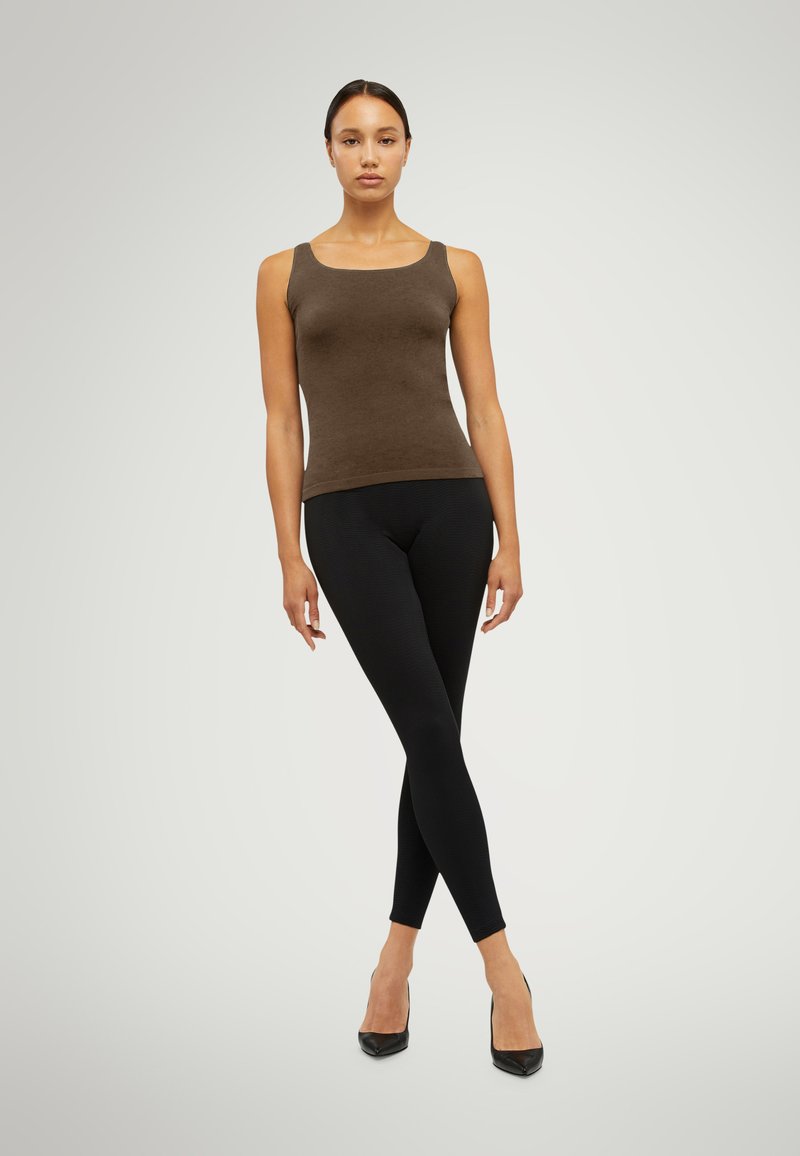 Brun, åtsittande linne med fyrkantig halsringning, parat med svarta, ribbade leggings och svarta stilettklackar. Enkelt mönster, sömlös textur.