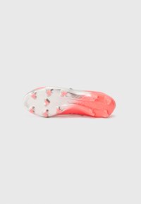 Scarpe da calcio con una suola bianca e rosa texturizzata, caratterizzate da un evidente motivo di trazione e da tacchetti triangulari per una migliore aderenza.