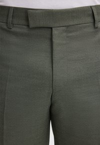 Pantaloni sartoriali verde oliva con texture liscia, pancia piatta e passanti per cintura. Il tessuto sembra leggero e strutturato.