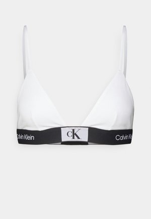 Valkoinen kolmion muotoinen bralette, joka on valmistettu pehmeästä puuvillasta. Siinä on ohuet olkaimet ja musta elastinen nauha, jossa on Calvin Klein -logo valkoisena ja harmaana.