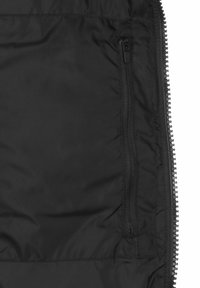 Interno di una giacca nera isolata con una tasca con zip, realizzata in tessuto morbido e con cuciture a contrasto lungo le cuciture.