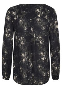 Blouse noire à manches longues avec un motif éclaboussé abstrait en blanc et vert foncé, comportant de légères plis au dos et un ourlet arrondi.