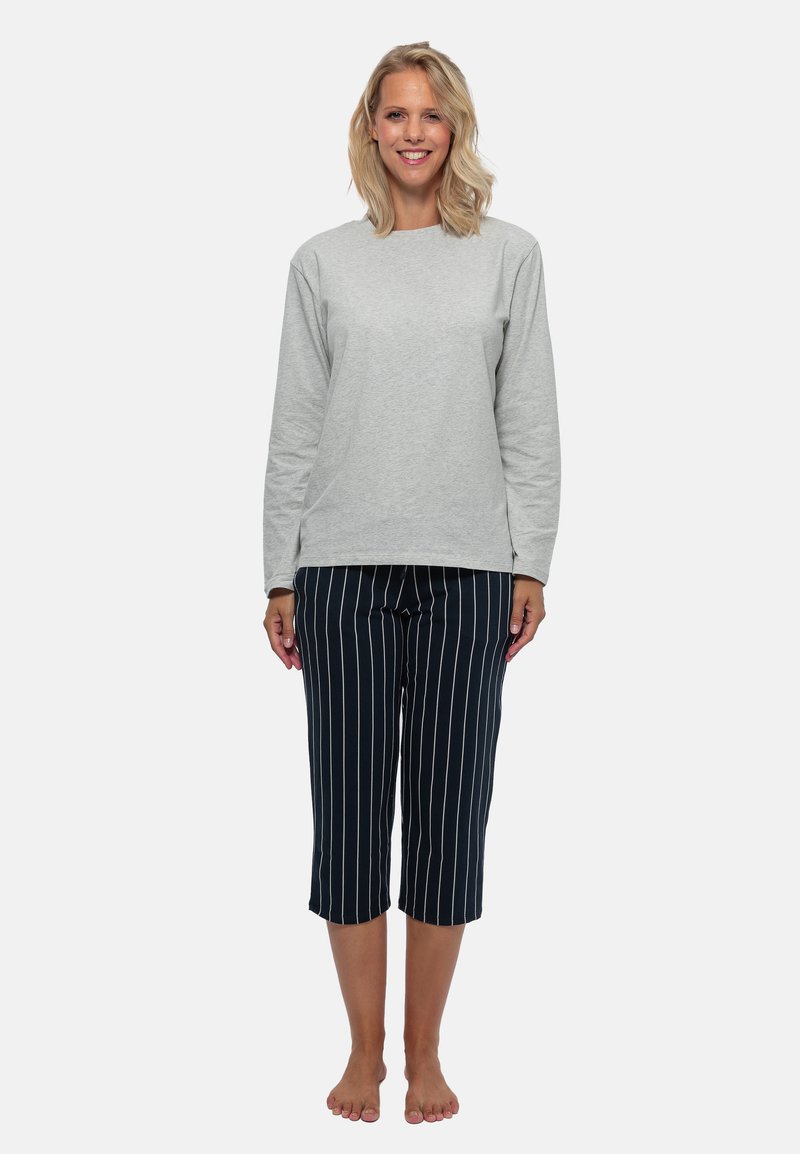 Grå langærmet top og marineblå stribede capribukser. Stoffet ser blødt ud; bukserne har lodrette hvide striber. Fødderne er bare.