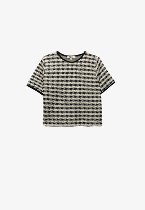Haut à manches courtes présentant un motif à carreaux noir et crème, avec un tissage texturé et une bordure noire contrastante le long de l'encolure et des manches.