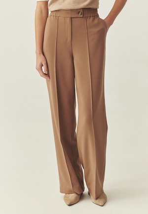 Bukser med vide ben i kamelfarvet stof, med en høj talje med knap, lodrette folder og en glat tekstur.