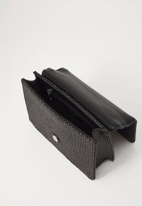 Borsa nera intrecciata con parte superiore in pelle liscia, design aperto, tasca con zip all'interno e un accento hardware circolare sul davanti.