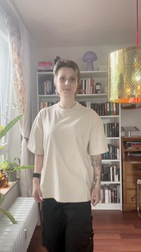 Heledbeez värvi ülemõõtu T-särk lühikeste varrukatega ja ümmarguse kaelusega, millel on rinna peal nüansirikka tekst. Mustad cargo-püksid.