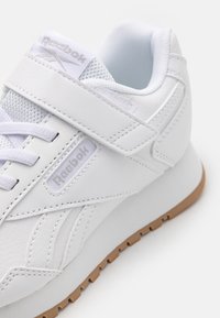 Baskets Reebok blanches avec une tige en cuir texturé et en mesh, dotées d'une bande auto-agrippante, de lacets et d'une semelle en caoutchouc beige.