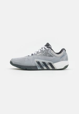 Sneaker sportiva grigia e nera con tomaia in mesh, lacci bianchi e suola bianca, mostrata in profilo su sfondo semplice.
