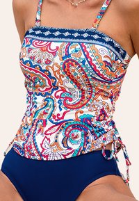 Haut de maillot de bain coloré à motifs avec liens sur les côtés, présentant un design paisley bleu et multicolore, des bretelles réglables et un bas uni bleu marine.