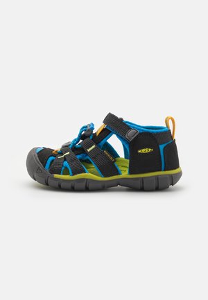 Black and blue sandal with adjustable straps, a textured upper, and a thick green sole. Features a pull tab and breathable design.