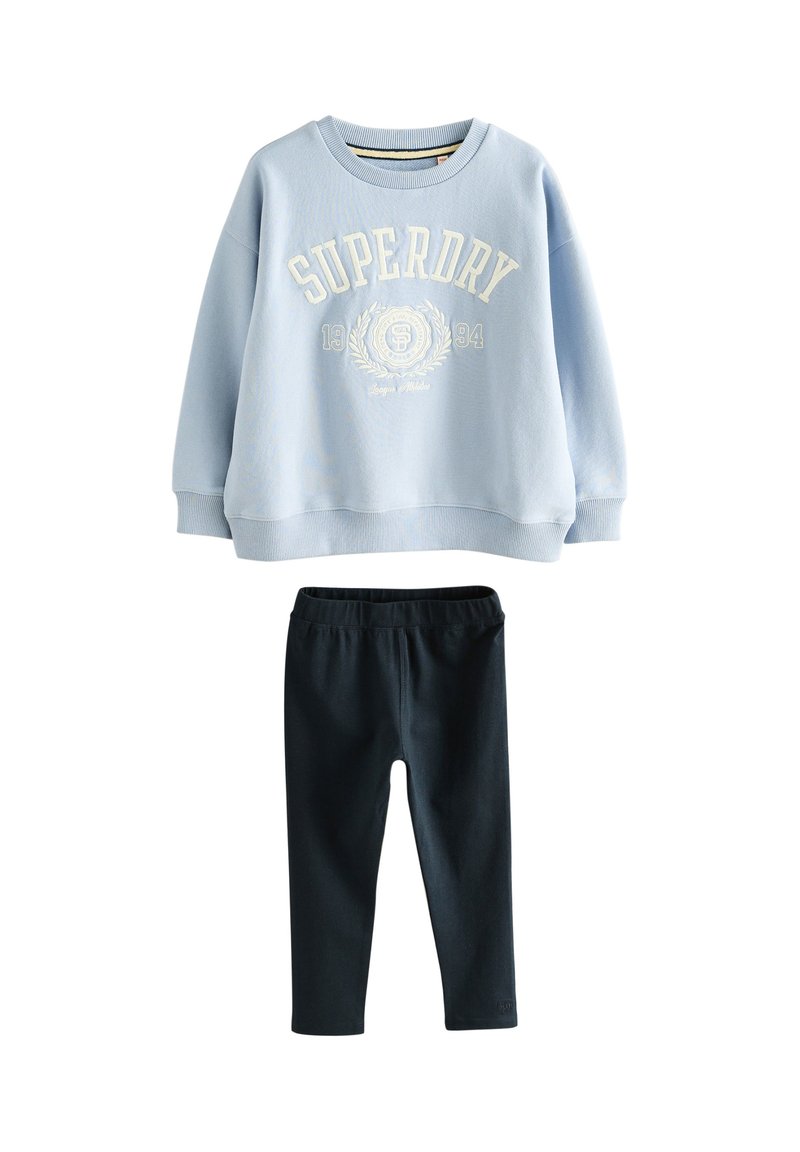 Šviesiai mėlynas džemperis su briaunuotais rankogaliais, ant kurių balta spalva užrašytas "SUPERDRY" tekstas ir logotipas, derinamas su juodomis tampriomis tamprėmis.