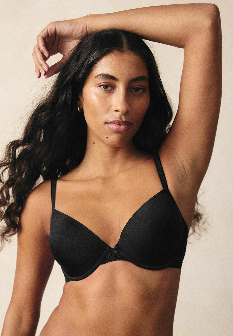 Reggiseno imbottito nero con spalline regolabili e dettagli in pizzo nel sottobusto. Texture liscia con una classica forma a coppa triangolare.