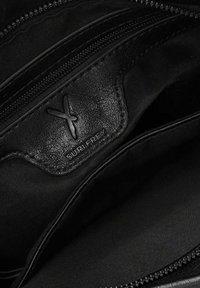 Černá texturovaná kožená taška uvnitř se zipy, s logem umístěným v rohu. Hladká látková podšívka, minimalistický design.