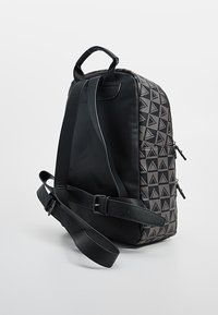 Zaino nero con motivo triangolare testurizzato, doppia cerniera, manico superiore e tracolla regolabile per un trasporto versatile.