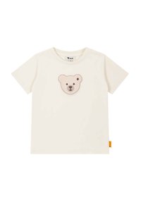 Camiseta de algodón crema con un suave parche bordado de la cara de un oso en marrón claro y marrón oscuro en el pecho. Mangas cortas y escote redondo.