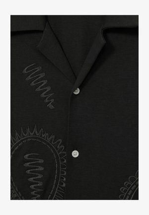 Čierna košeľa s textúrovaným vzorom, zdobená vyšívanými vírmi a kruhovými motívmi, doplnená bielymi gombíkmi. Mäkká tkanina, s golierom.