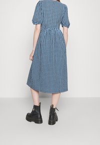 Blå och svart rutig midiklänning med puffärmar, åtsittande midja och utsvängd kjol. Bärs med svarta snörda kängor.